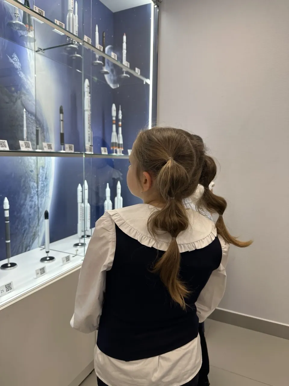 Посетительница у витрины с моделями ракет